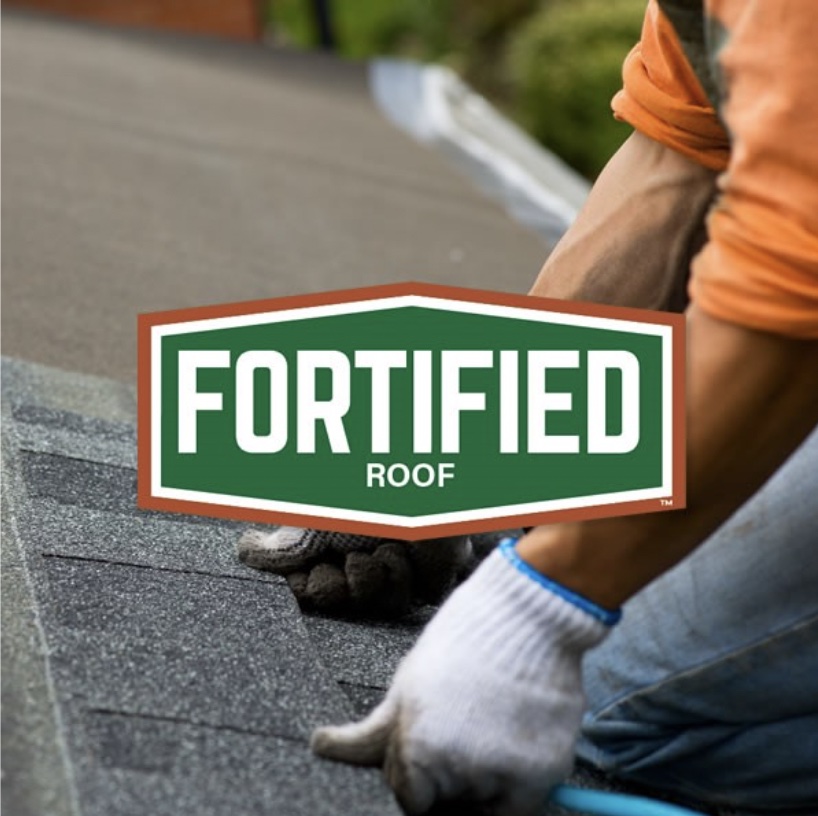 Red and green fortified logo on top of a photo depicting a person's hands in gloves installing shingles onto a roof.